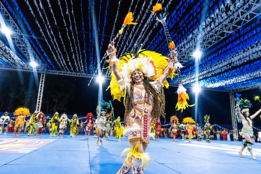 Brincante do Boi do Favela com cocar amarelo de plumas dança na arena durante a temporada 2026