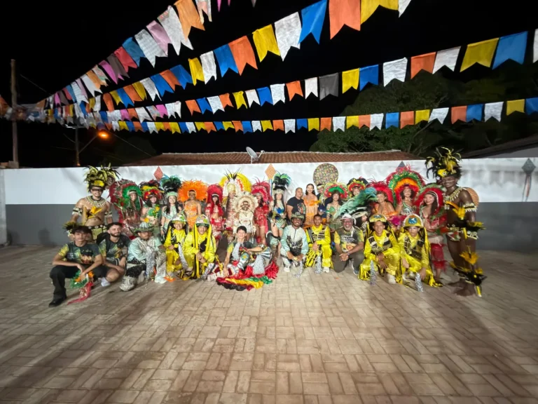Grupo completo do Boi do Favela posado sob bandeirinhas juninas depois da apresentação