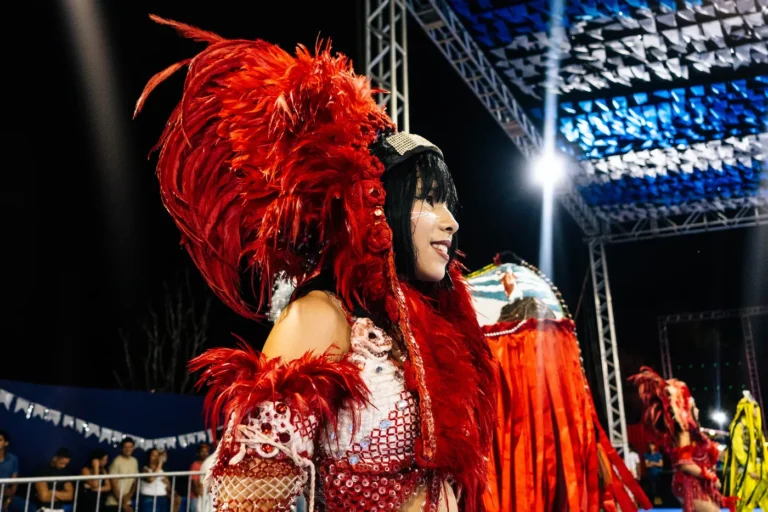 Brincante do Boi do Favela com grande cocar vermelho de plumas durante a apresentação