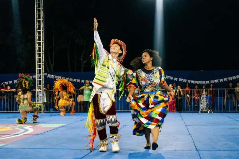 Casal de brincantes do Boi do Favela dança com figurinos tradicionais coloridos