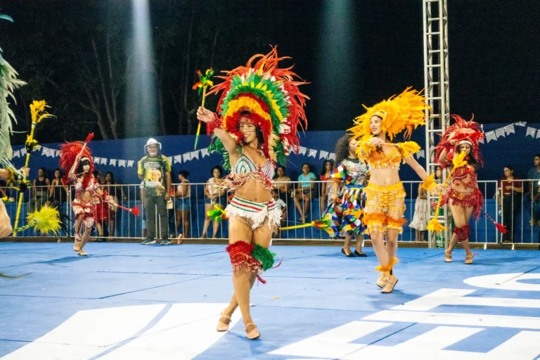 Dançarina do Boi do Favela gira com cocar verde e vermelho durante a apresentação