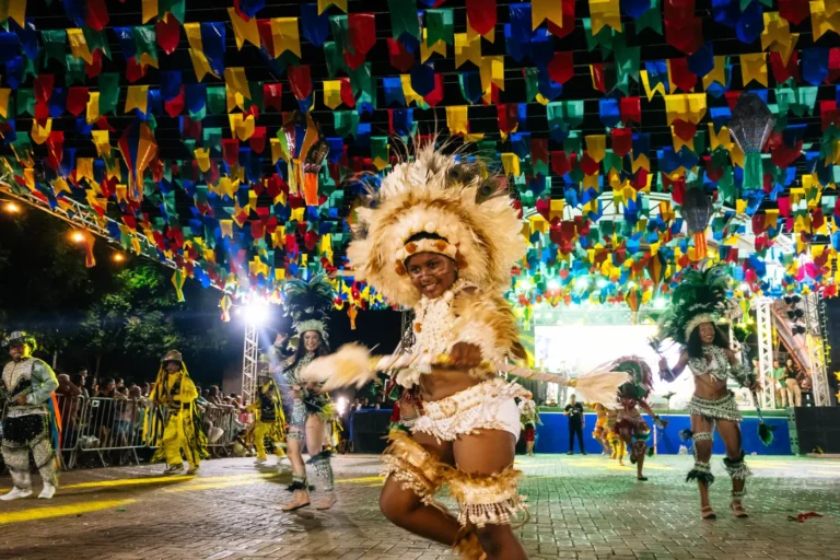 Dançarina do Boi do Favela em movimento com figurino claro e cocar de plumas