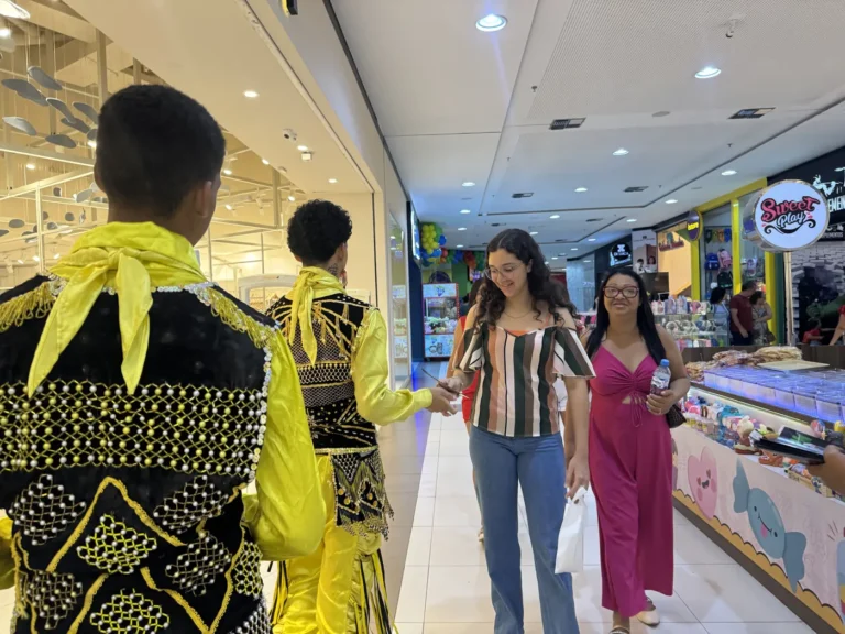 Dançarinos com figurino amarelo cumprimentam o público nos corredores do Imperial Shopping durante a mostra cultural
