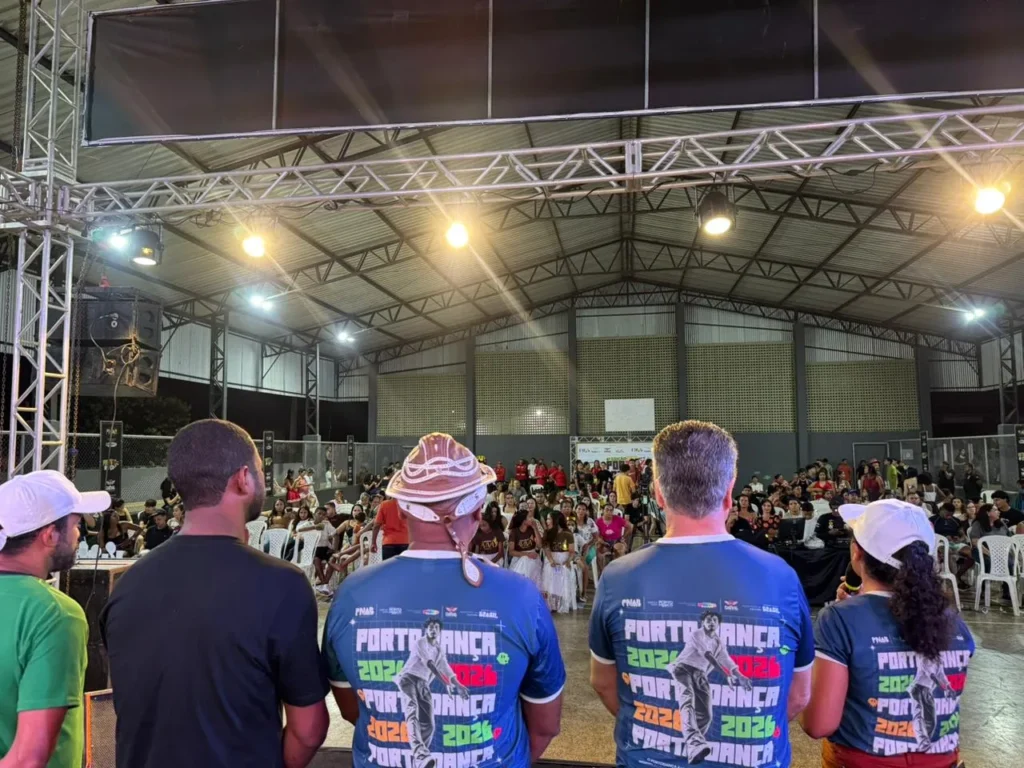 Equipe do Porto Dança 2026 de camiseta azul diante da plateia lotada no festival