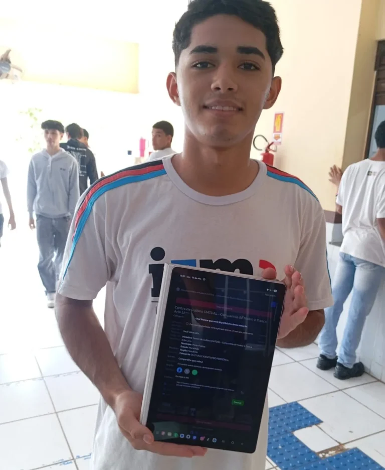 Estudante mostra o celular com a página de votação do Prêmio Periferia Viva aberta