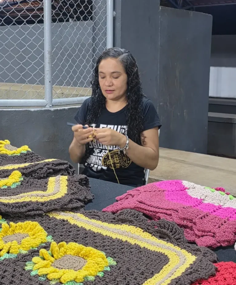 Artesã trabalha em peças de crochê coloridas no estande da feira afro