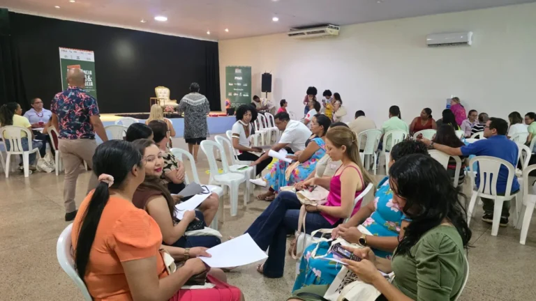 Participantes acompanham atividade de formação sentados em roda, com material em mãos