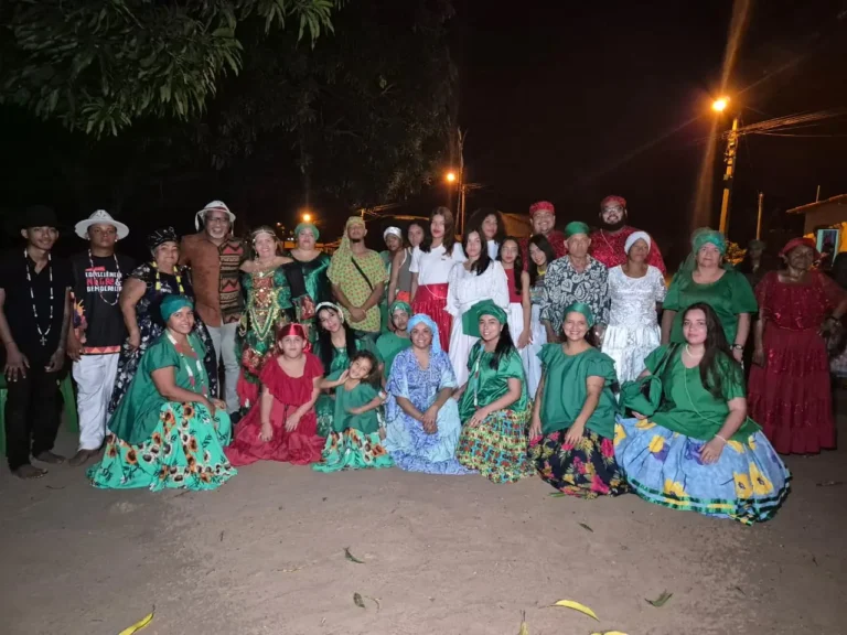 Grupo cultural com figurinos posa à noite depois da apresentação em praça pública