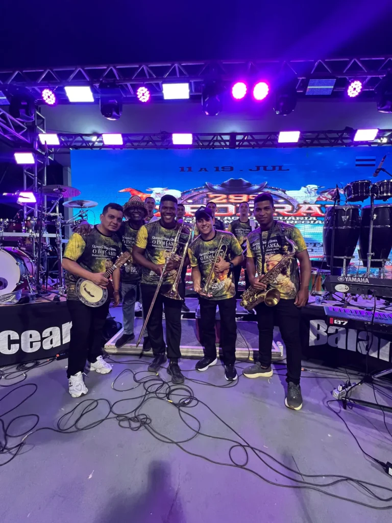 Músicos da orquestra do Boi do Favela no palco com banjo, saxofone e trompete