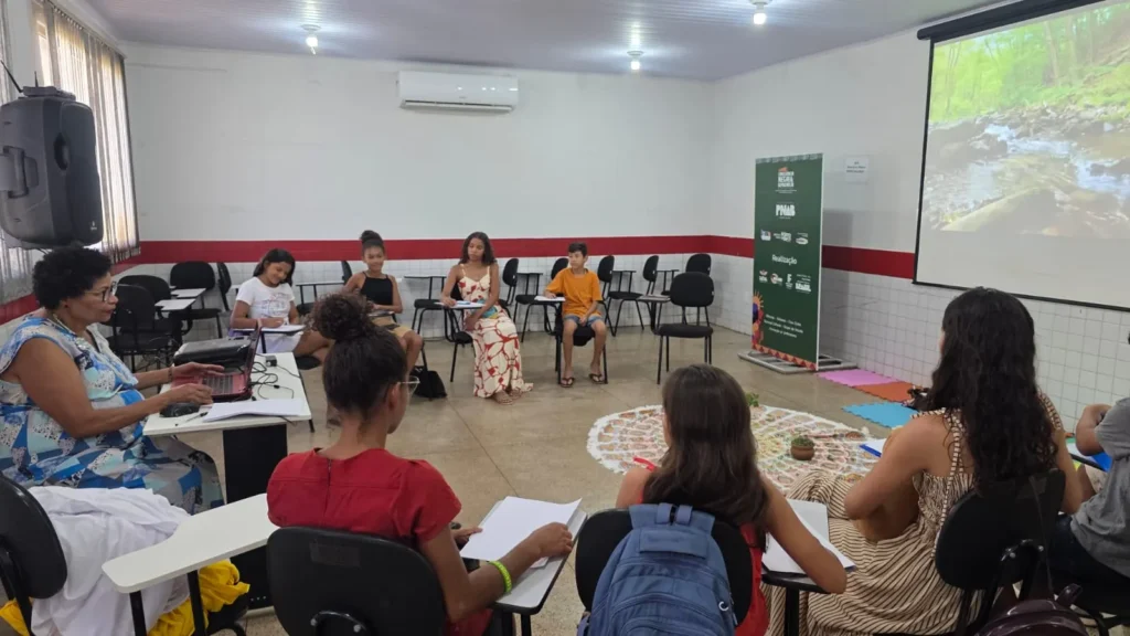 Estudantes sentados em roda participam de oficina em sala de aula