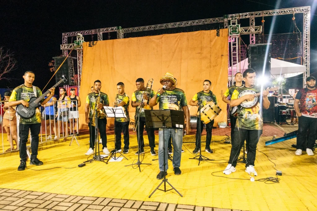 Músicos da orquestra do Boi do Favela tocam instrumentos de sopro e percussão diante do palco
