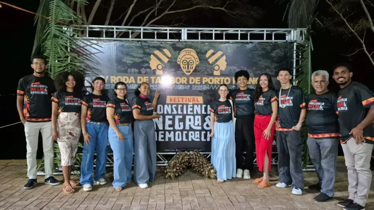 Grupo posa diante do painel do Movimento Consciência Negra e Democracia na Roda de Tambor