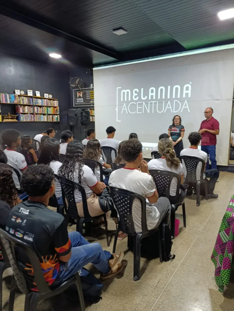 Público assiste a uma atividade de formação do movimento em espaço com estantes de livros