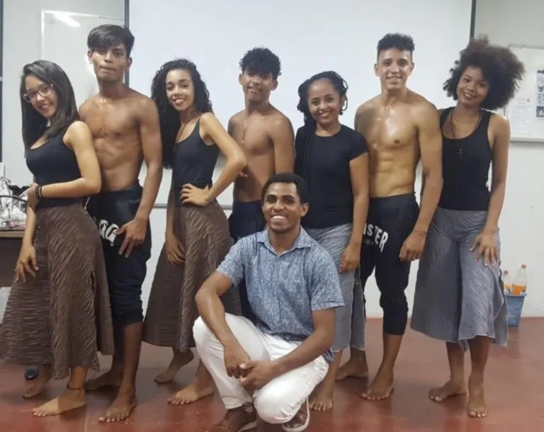 Grupo de dança da CIATDAL reunido depois do ensaio, com o fundador Edvan da Silva Oliveira agachado à frente